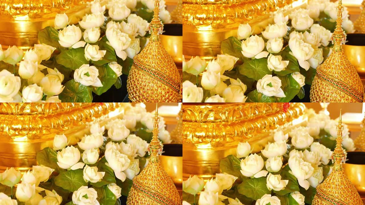 祭坛上的鲜花和金色装饰。美丽的白莲花和金色的皇家装饰品放在泰国的传统祭坛上。君主制的象征。