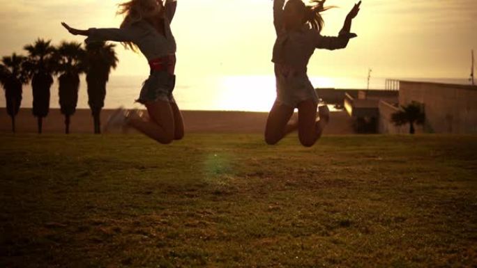 快乐的姐妹或朋友在海滩上跳跃享受日落
