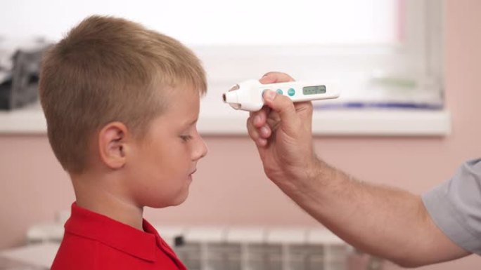 医生在医院用红外温度计测量男孩的体温。体检