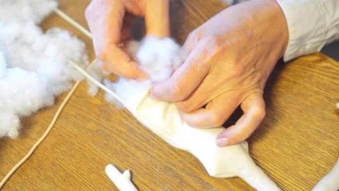 手工娃娃的制作。女人用合成防冬器填充娃娃细节。