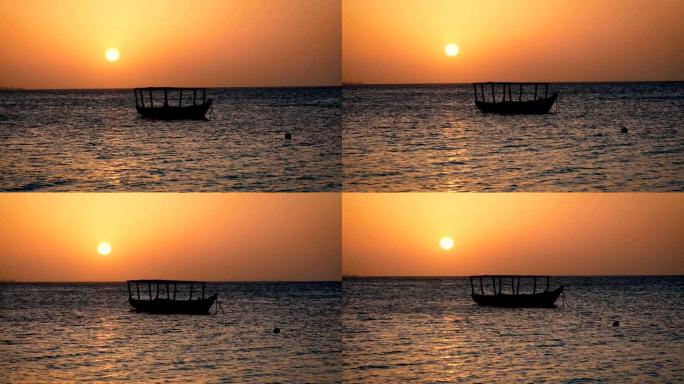渔船的轮廓在日落时大红太阳的海浪上摆动