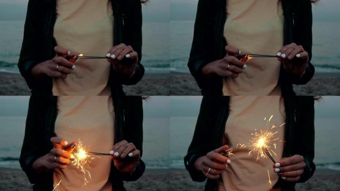 一个女孩的特写镜头晚上在海滩上点燃烟火，慢动作