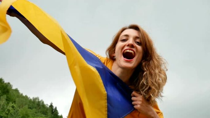 情绪激动的年轻女子举着蓝色和黄色的乌克兰国旗在天空的背景