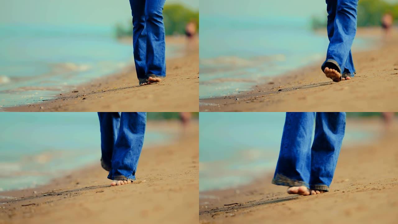 穿着湿牛仔裤和赤脚的女人走在沙滩上的沙滩上。沿着海边散步。特写。