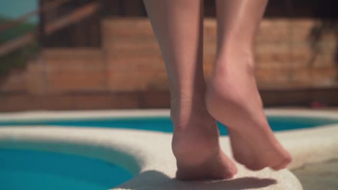 女人在游泳池边缘tip脚时的双腿特写。