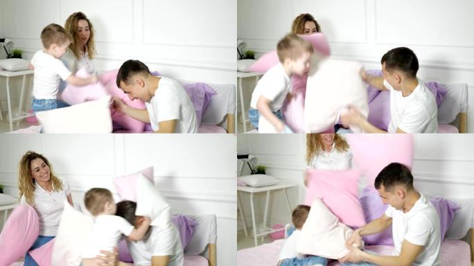 年轻的家庭: 爸爸妈妈和小儿子在床上玩枕头大战。