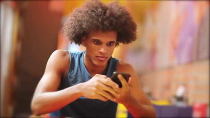 年轻英俊的黑人拿着手机。非洲男子正在检查智能手机的微笑