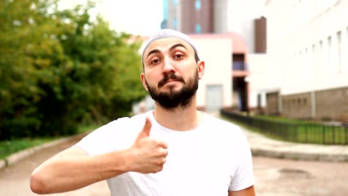 英俊快乐的大胡子穆斯林男子在镜头前竖起大拇指