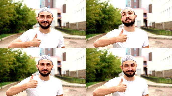 英俊快乐的大胡子穆斯林男子在镜头前竖起大拇指