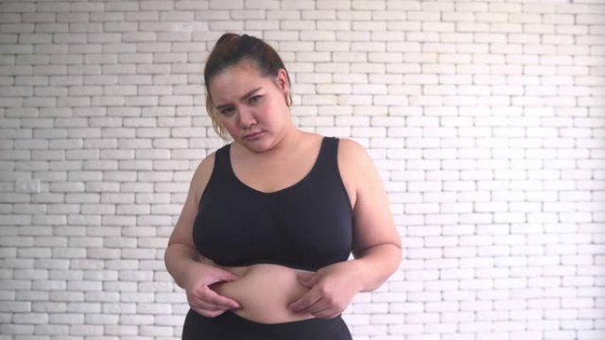 穿着健身布的泰国超重妇女摸着肚子感到无聊