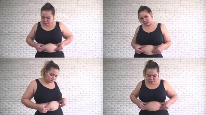 穿着健身布的泰国超重妇女摸着肚子感到无聊