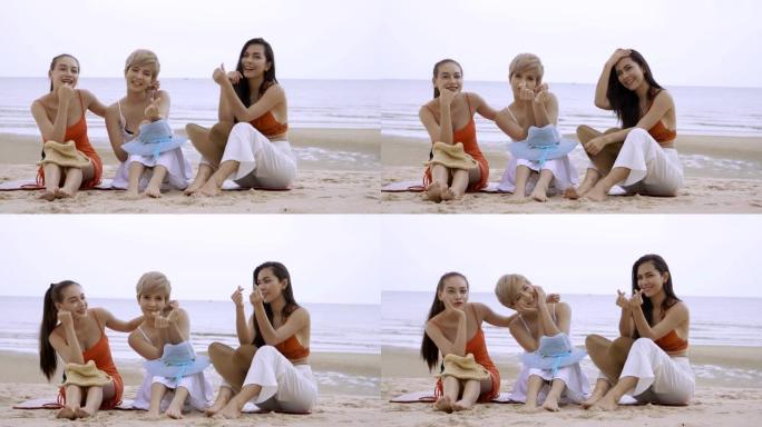 三个亚洲女性性感女孩坐在沙滩上微笑秀迷你心在手
