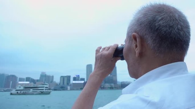 高年级男子用双筒望远镜看香港大厦