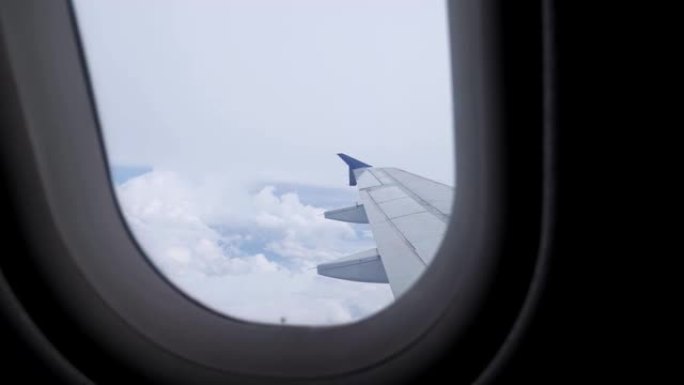 从飞机的窗户上看机翼，天空和云。