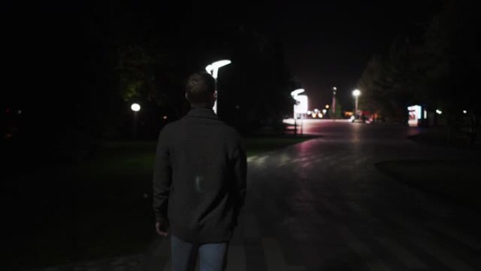 一个年轻人在傍晚沿着林荫大道行走。