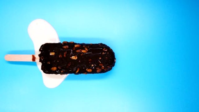 顶视图巧克力外冰棒与豌豆坚果融化在蓝色时间流逝