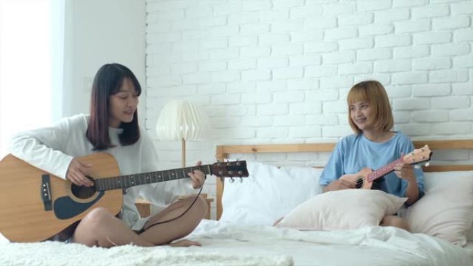 青少年女友在早晨的阳光下在白色房间的床上弹吉他