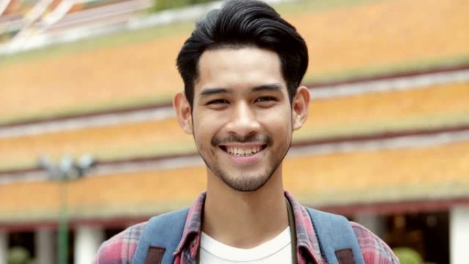 微笑肖像英俊的年轻亚洲男子游客旅游和拍照在寺庙泰国。亚洲男子博客愉快享受休闲生活方式旅游。
