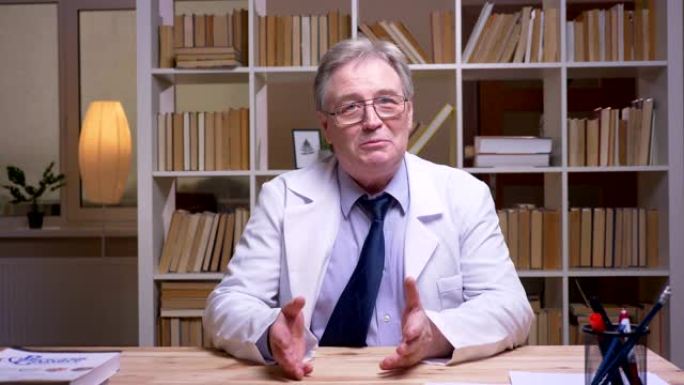采访穿着白大褂的高级医生在书架背景上对着镜头说话。