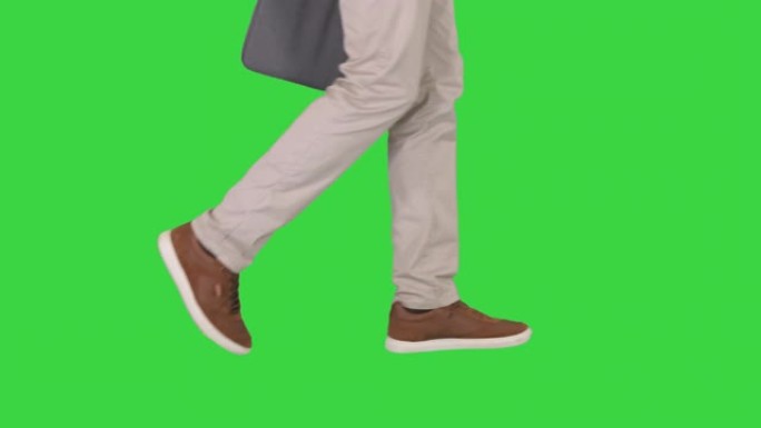 男人的脚在绿色屏幕上穿着牛仔裤和运动鞋行走，色键