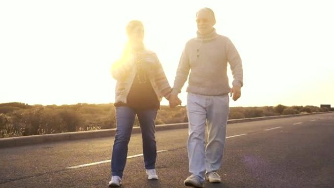 成年成熟夫妇waling手牵手与爱情和浪漫在背景式日落的街道上 -- 永远在一起的概念，让人们享受生