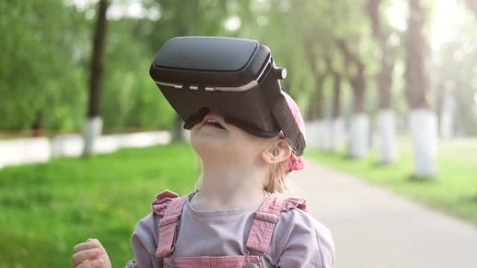 小高加索女孩4-5年使用虚拟现实眼镜耳机在大自然。