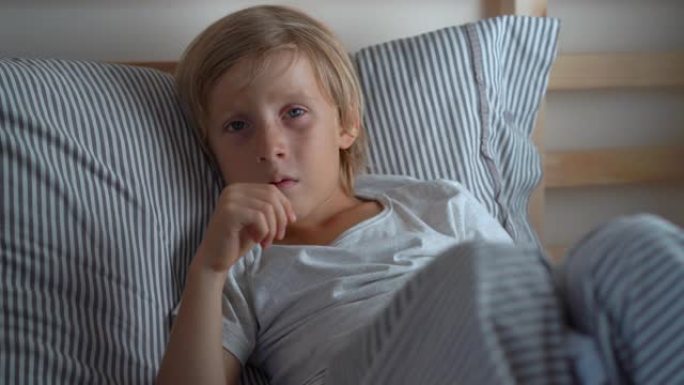 生病的小男孩躺在床上。男孩在床上咳嗽。婴儿流感概念
