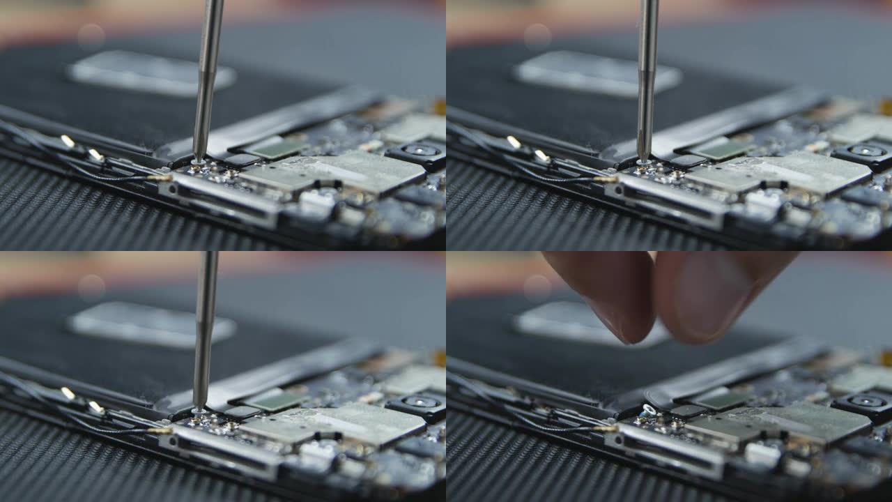 显示手机维修过程的特写镜头。修理工用螺丝刀拧出螺丝。智能手机的内部组件。拆解的手机。