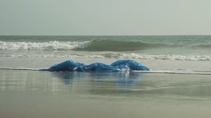 塑料污染在海滩上冲刷聚乙烯防水布