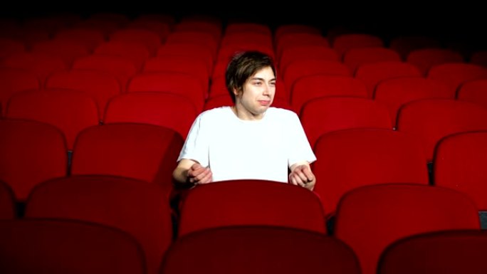 一个人独自坐在空荡荡的电影院里，不高兴