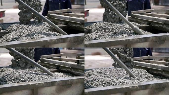 工人在建筑工地上将混凝土倒入大型钢模中