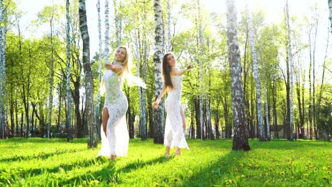 阳光照射在伯奇格罗夫跳舞的两个穿着性感礼服的年轻女人身上