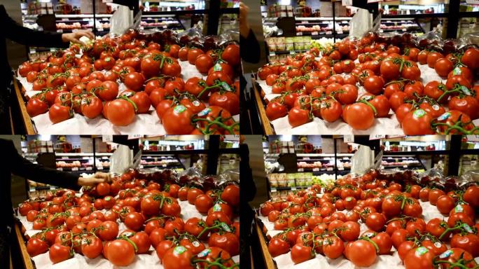 女人从超市的展示中选择新鲜西红柿。