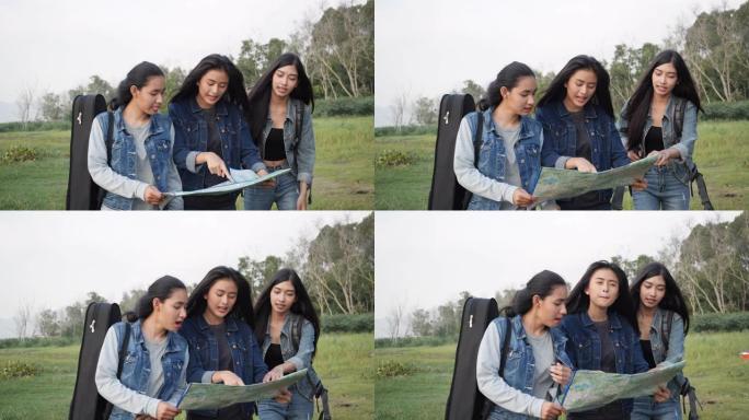 三个亚洲年轻女性一起拿着一张纸质地图在夏天的湖里航行。旅行者监控旅行路线。旅游度假、导航和地理概念。