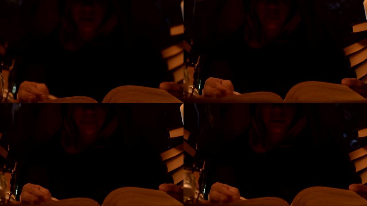 近距离的女孩魔术师在一个黑暗的房间里，在烛光下读咒语。低调的现场摄像机。神秘的。