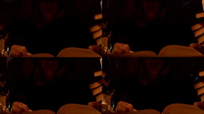 近距离的女孩魔术师在一个黑暗的房间里，在烛光下读咒语。低调的现场摄像机。神秘的。