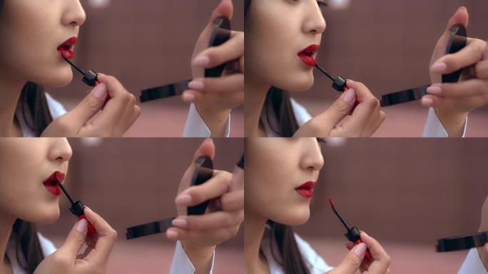 美丽的日本女孩用红色唇膏涂嘴唇。人看起来很棒。