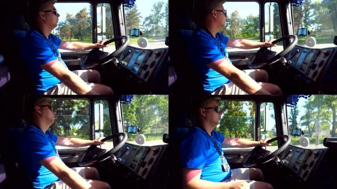 司机在卡车车厢内的侧视图，骑在乡间小路上，在阳光明媚的日子里享受旅程。戴着帽子和墨镜的男子控制着他的