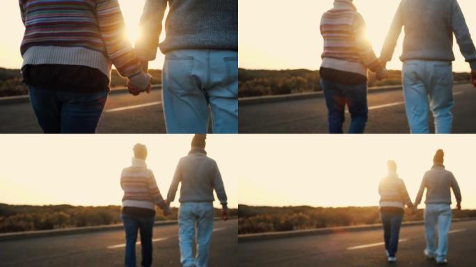 情侣走路用关系概念保持双手在一起-成熟的人永远在一起生活方式-漫长的道路上的休闲活动和背景中的金色日