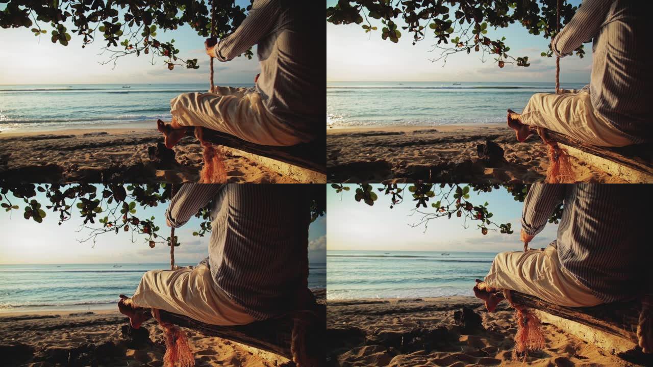 一个人坐在木秋千上享受着大海。