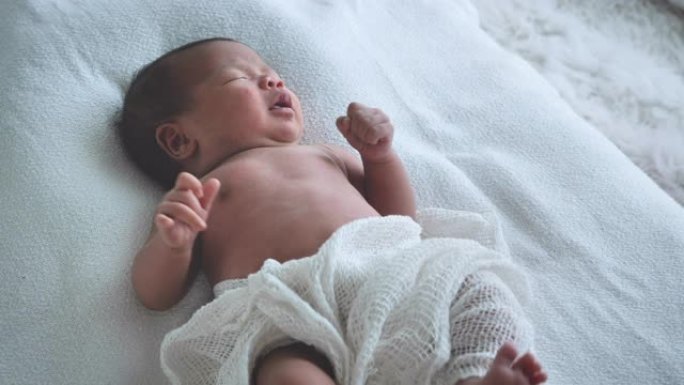 亚洲女性新生婴儿躺在床上，早晨晒太阳。可爱的小女孩三周大。微笑、哭泣、扭动、情感概念