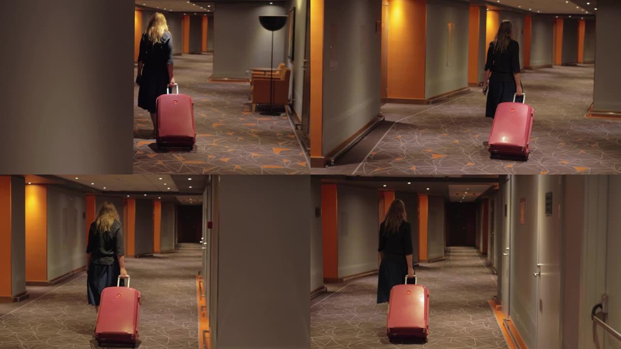 女人带着手提箱走到酒店走廊的房间