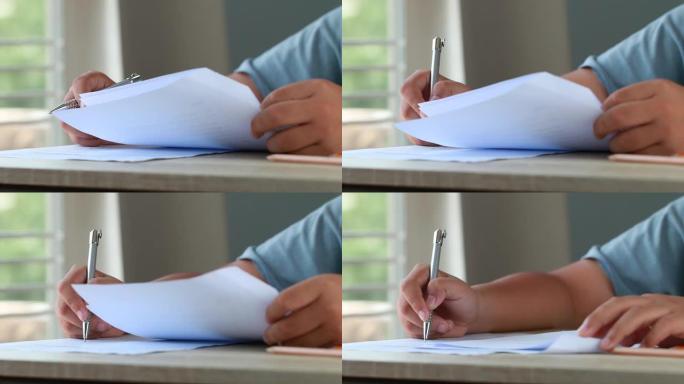 学校概念中的教育考试考试: 大学生在演讲台上拿着笔笔记纸质文件单，在考试教室里参加考试。课堂思想中的