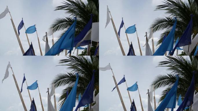 蓝旗随风飘扬。热带海滩多云天气下，小三角蓝旗随风飘扬