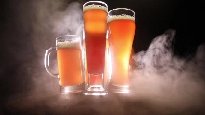 创意概念。木制桌子上的啤酒杯，深色的雾状背景。选择性聚焦