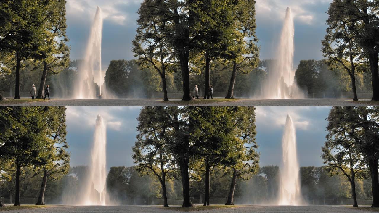 德国汉诺威。巨大的高喷水器从放在地上的碗中倒出。在公园绿树的背景下。泌尿外科疾病和前列腺炎的治疗概念