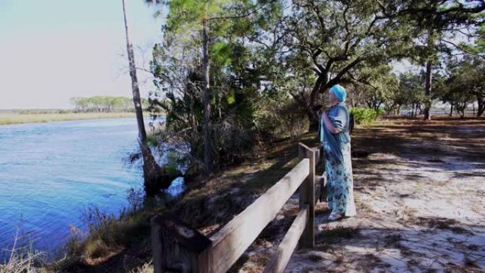 成熟的身体阳性妇女在北佛罗里达州Ochlockonee河州立公园用双目鸟观看鸟类
