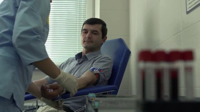 护士的手准备取病人的血液坐在扶手椅的背景。