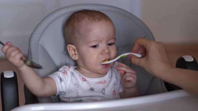 妈妈用勺子喂她可爱的宝宝。小男孩正在吃儿童粥