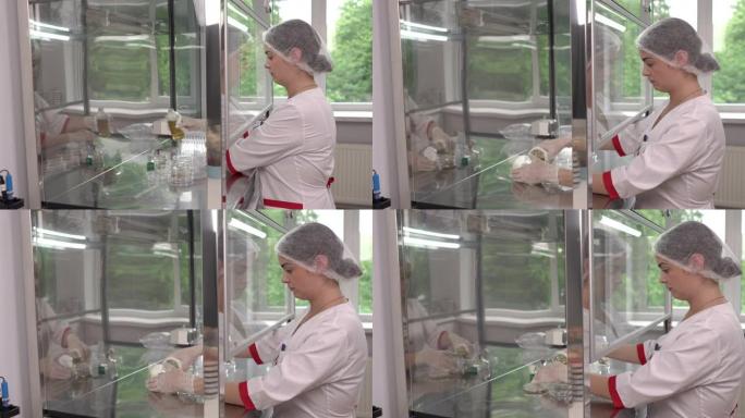 医学实验室的科学家在微生物极限检测室的层流柜中做微生物试验的侧视图。